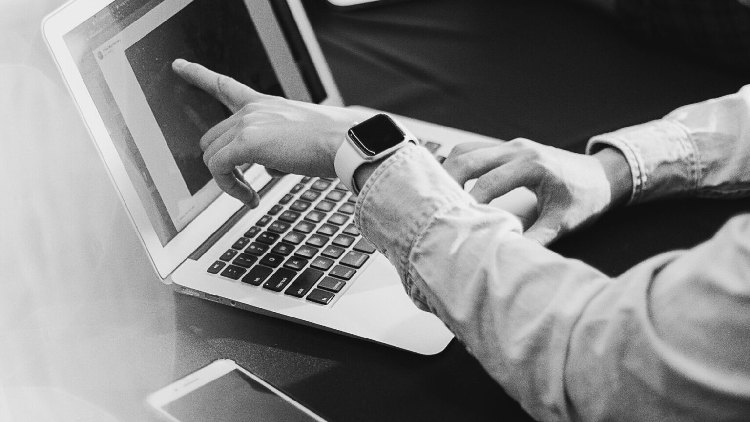 jemand zeigt etwas auf einem Laptop